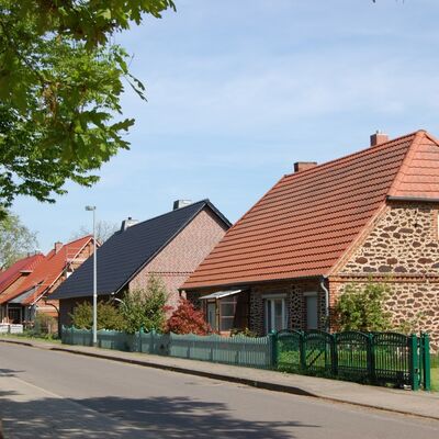Bild vergrößern: Auf diesem Bild ist die Häuserreihe entlang der Weselsdorfer Dorfstraße zu sehen. Links ragt zudem ein Baum in die Höhe.